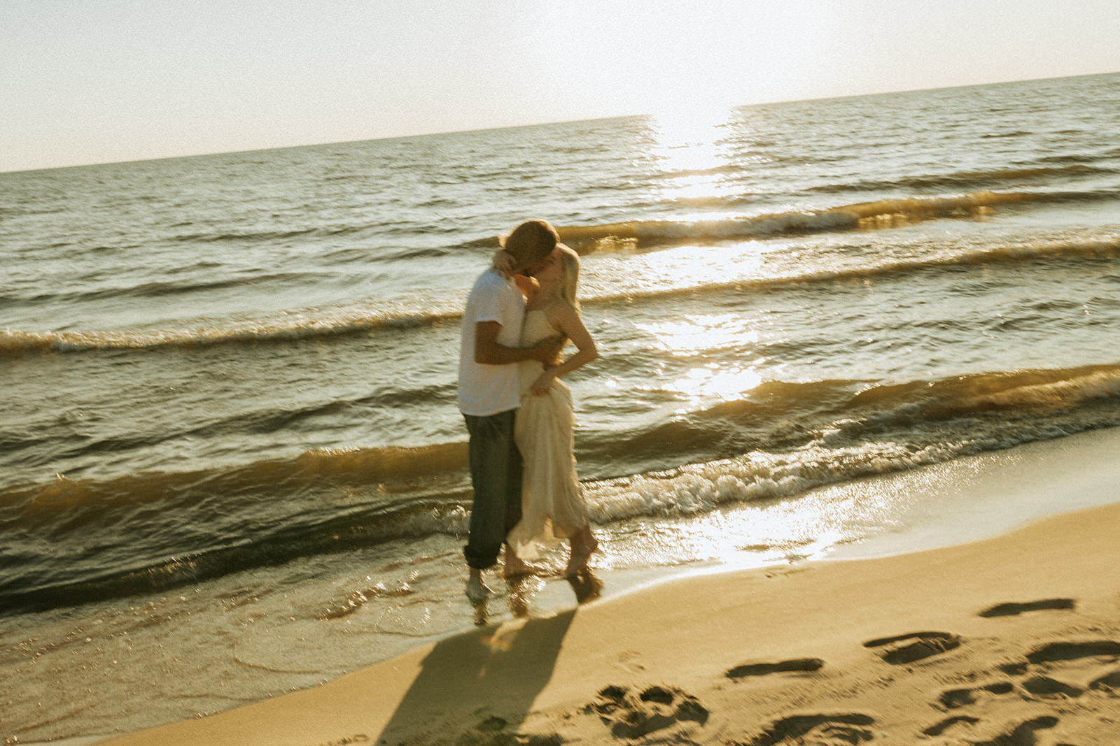 A couple taking engagement photos at a beautiful beach on Lake Michigan